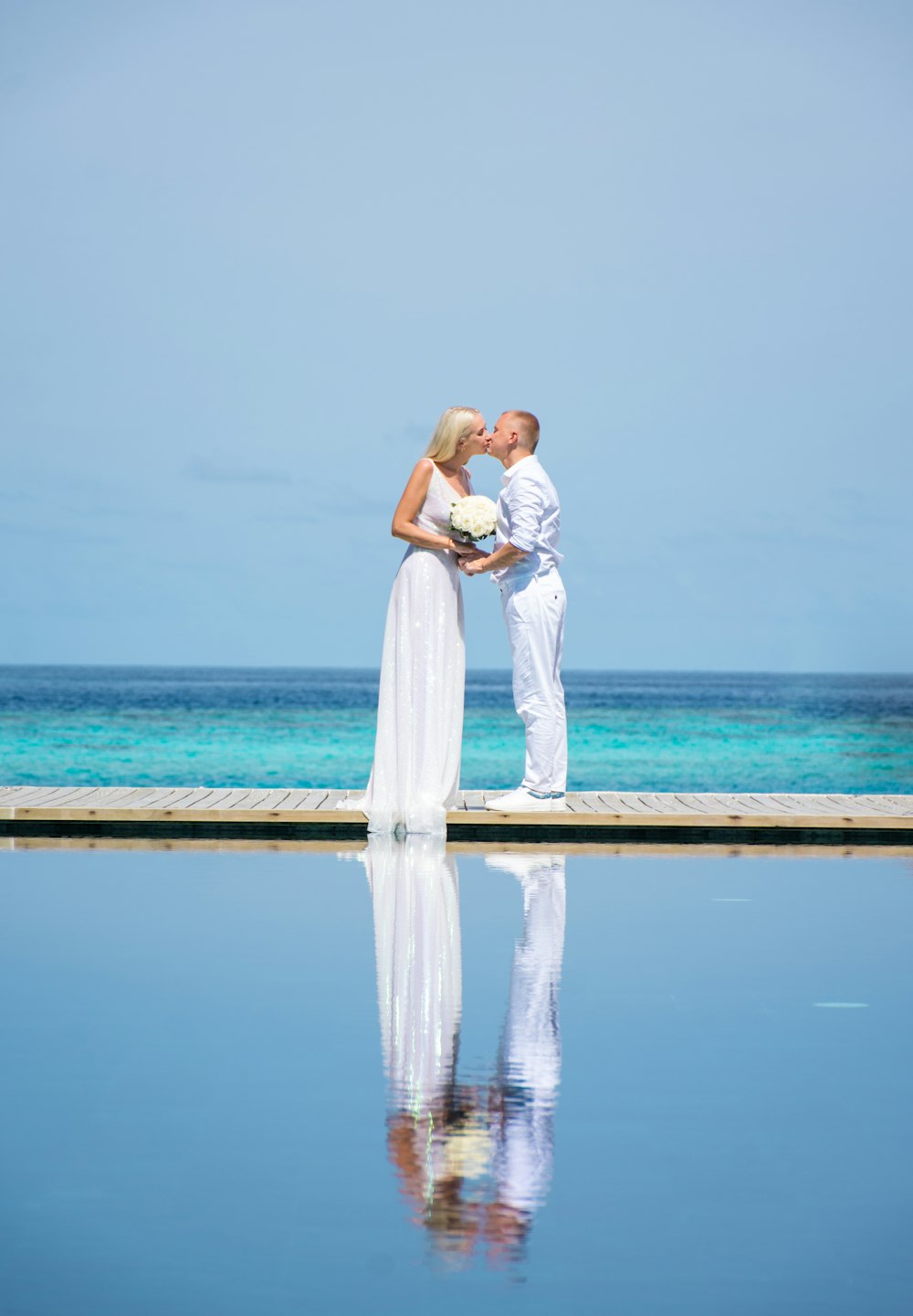 couple kissing on beach during daytime