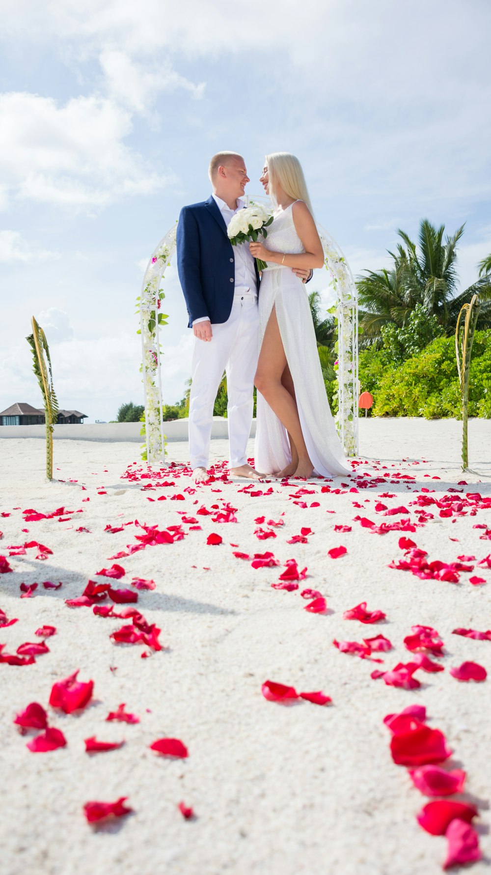 man in black suit and woman in white wedding dress walking on white sand during daytime