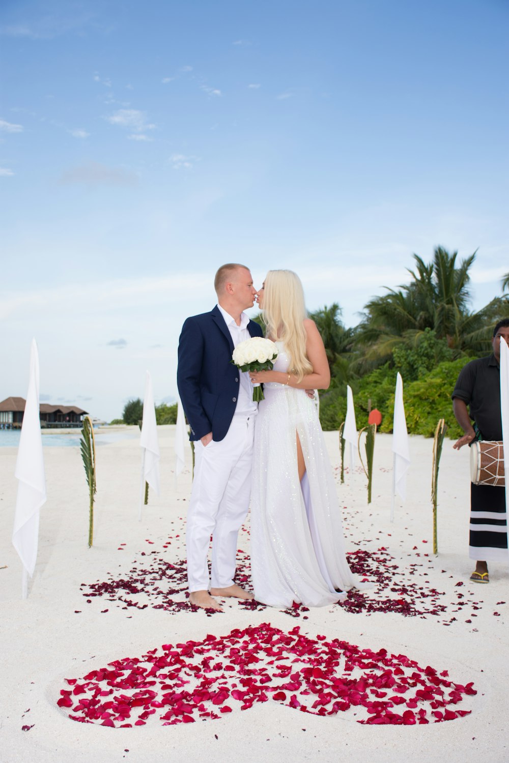 man in black suit and woman in white wedding dress walking on beach during daytime