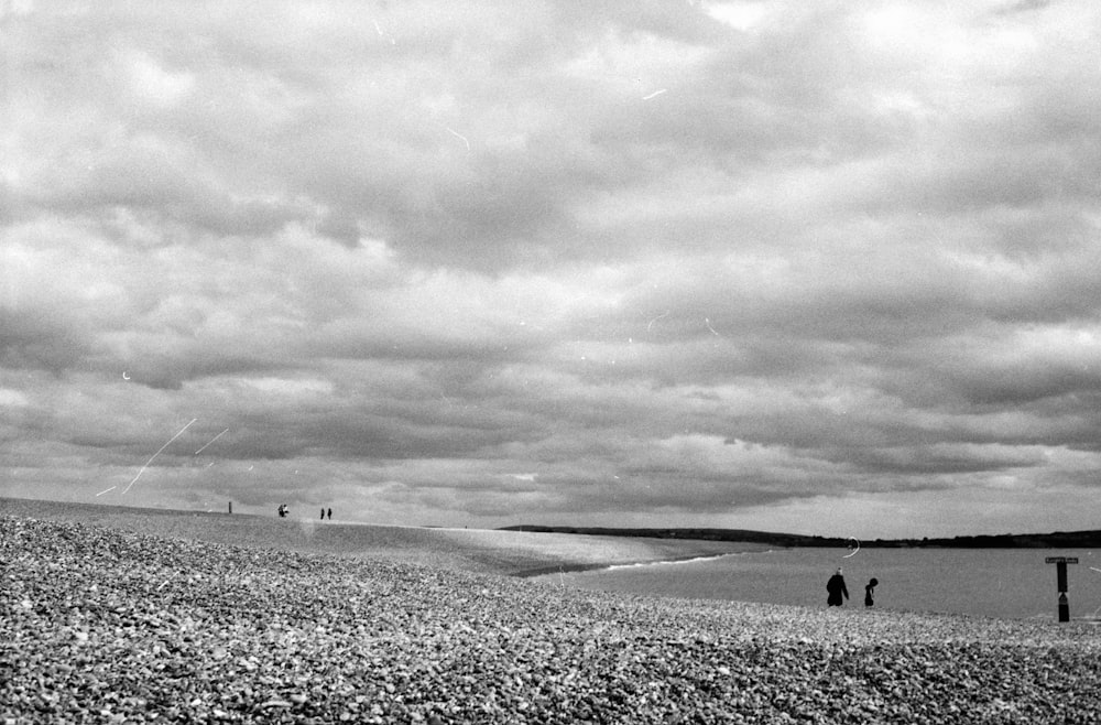 grayscale photo of people walking on snow covered field