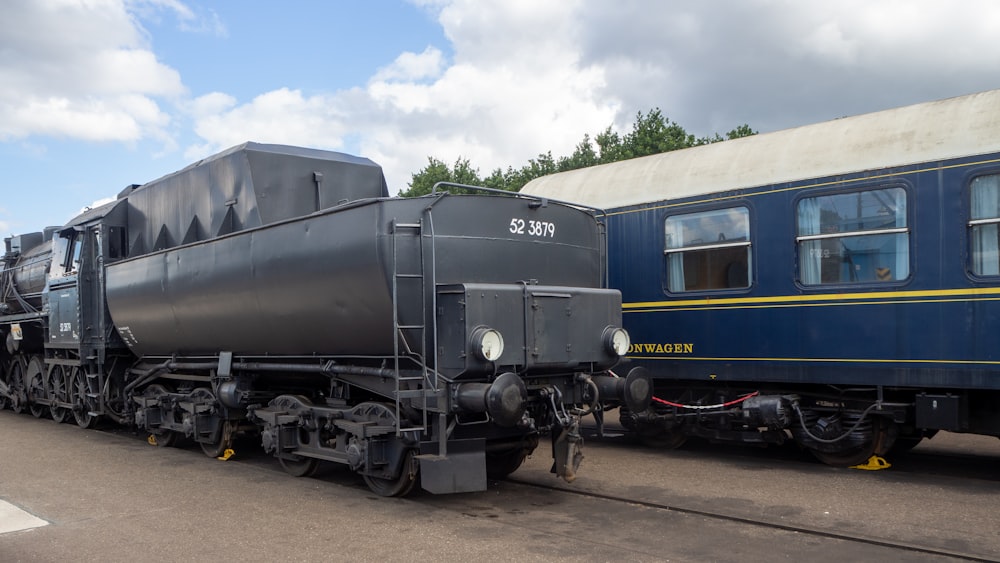 black and blue train on rail tracks under blue sky during daytime