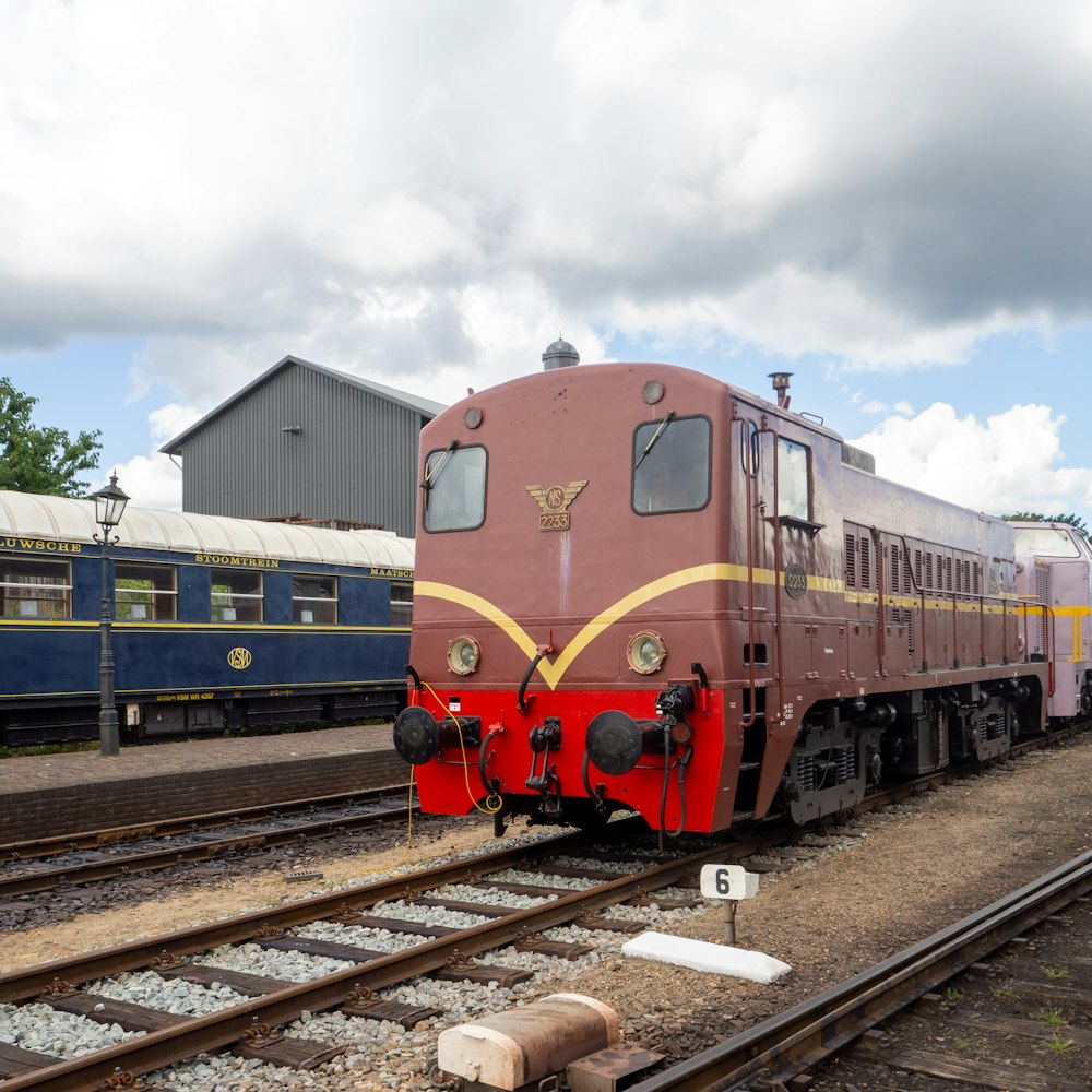 blue and red train on rail tracks under cloudy sky during daytime