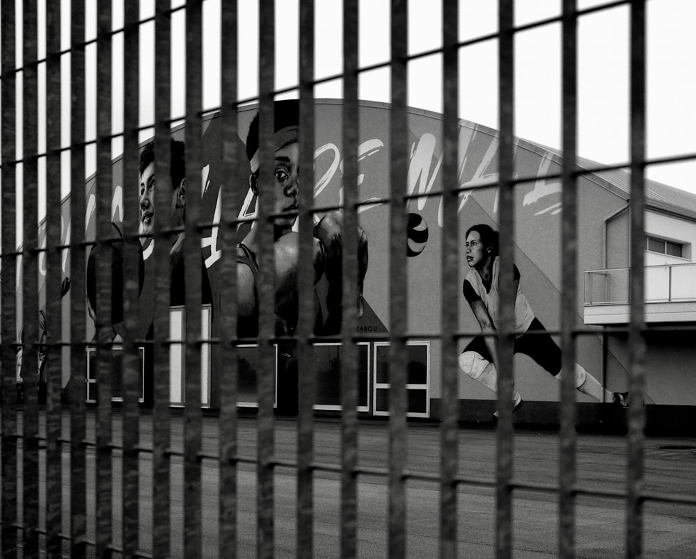 grayscale photo of 2 women standing beside metal fence