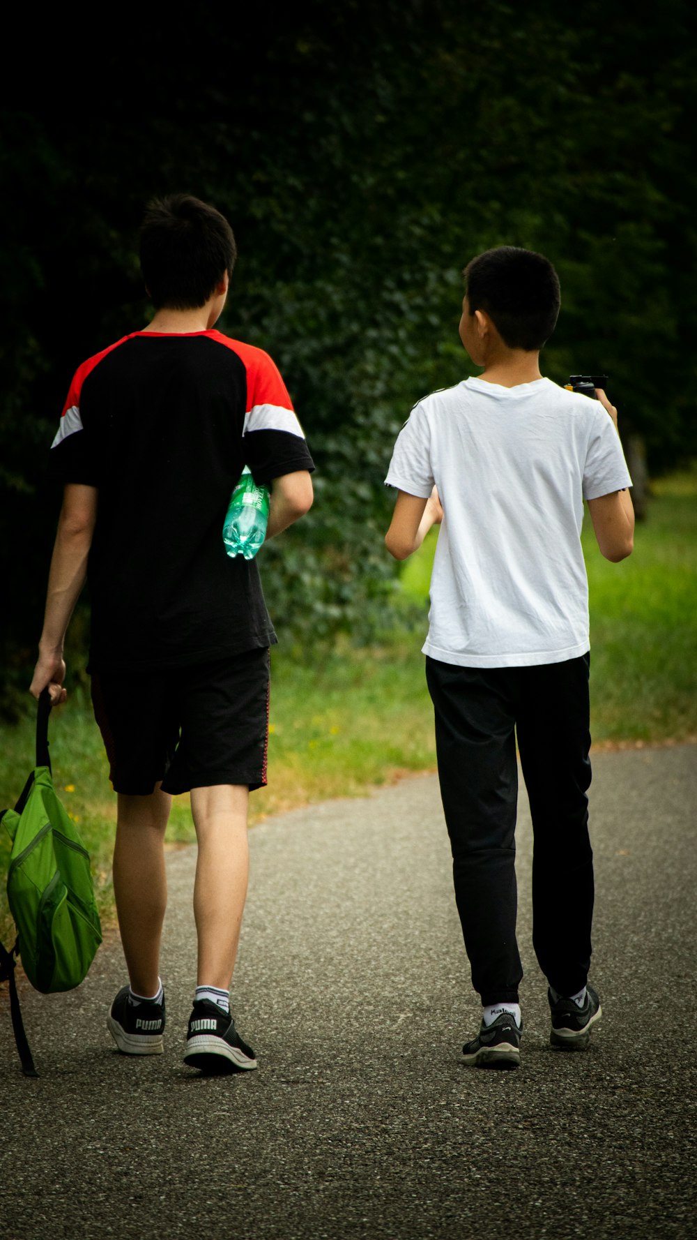 man in white crew neck t-shirt and black pants holding green plastic bag