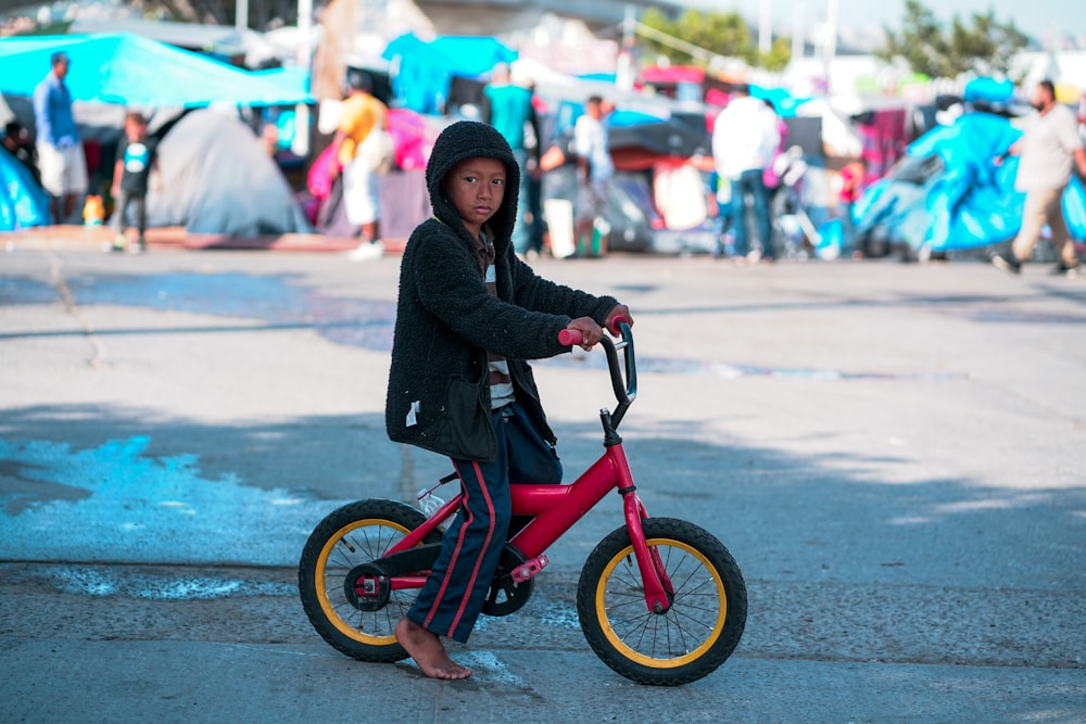 femme en veste noire sur un vélo rouge pendant la journée