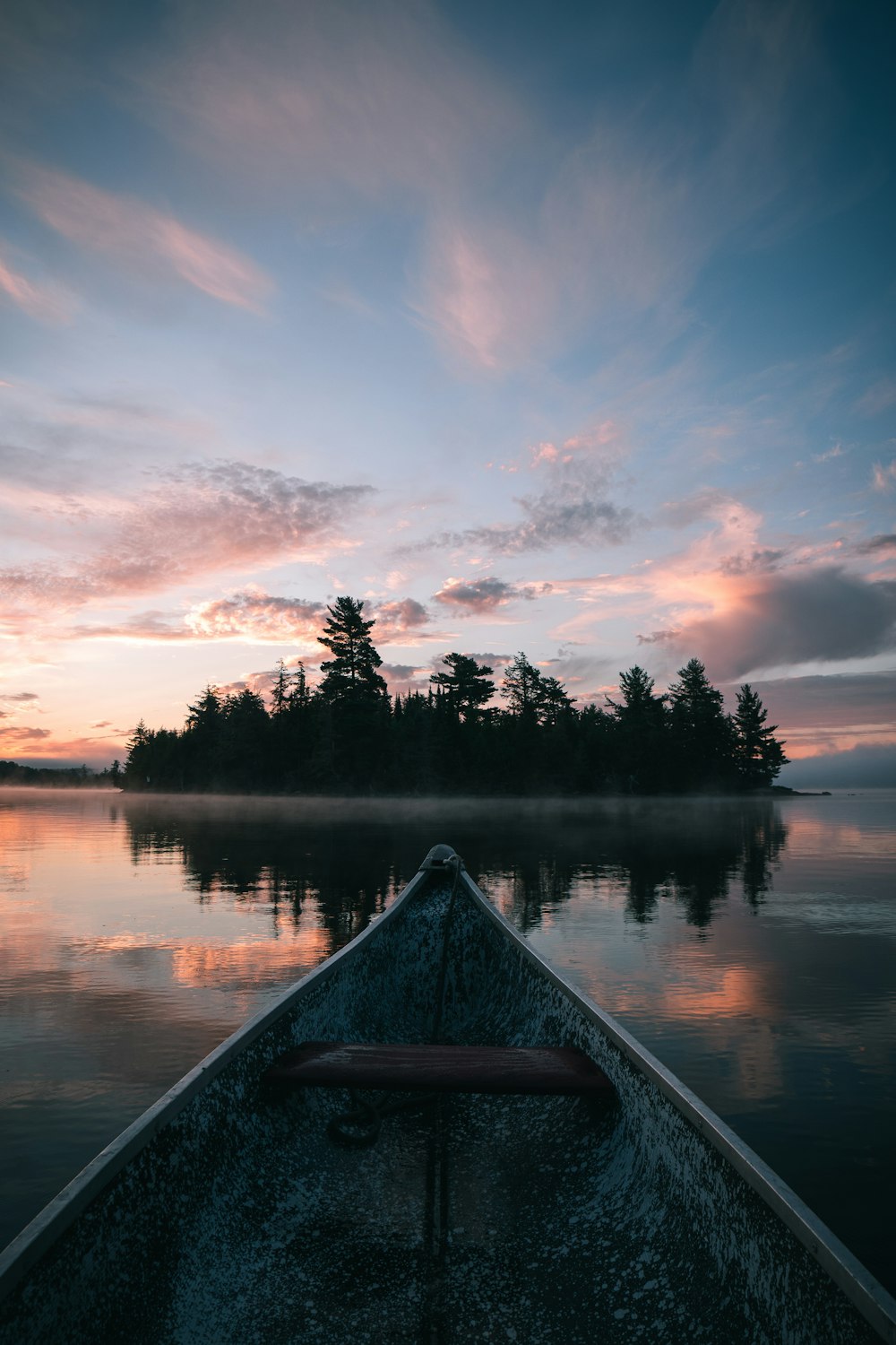brown canoe on lake during sunset