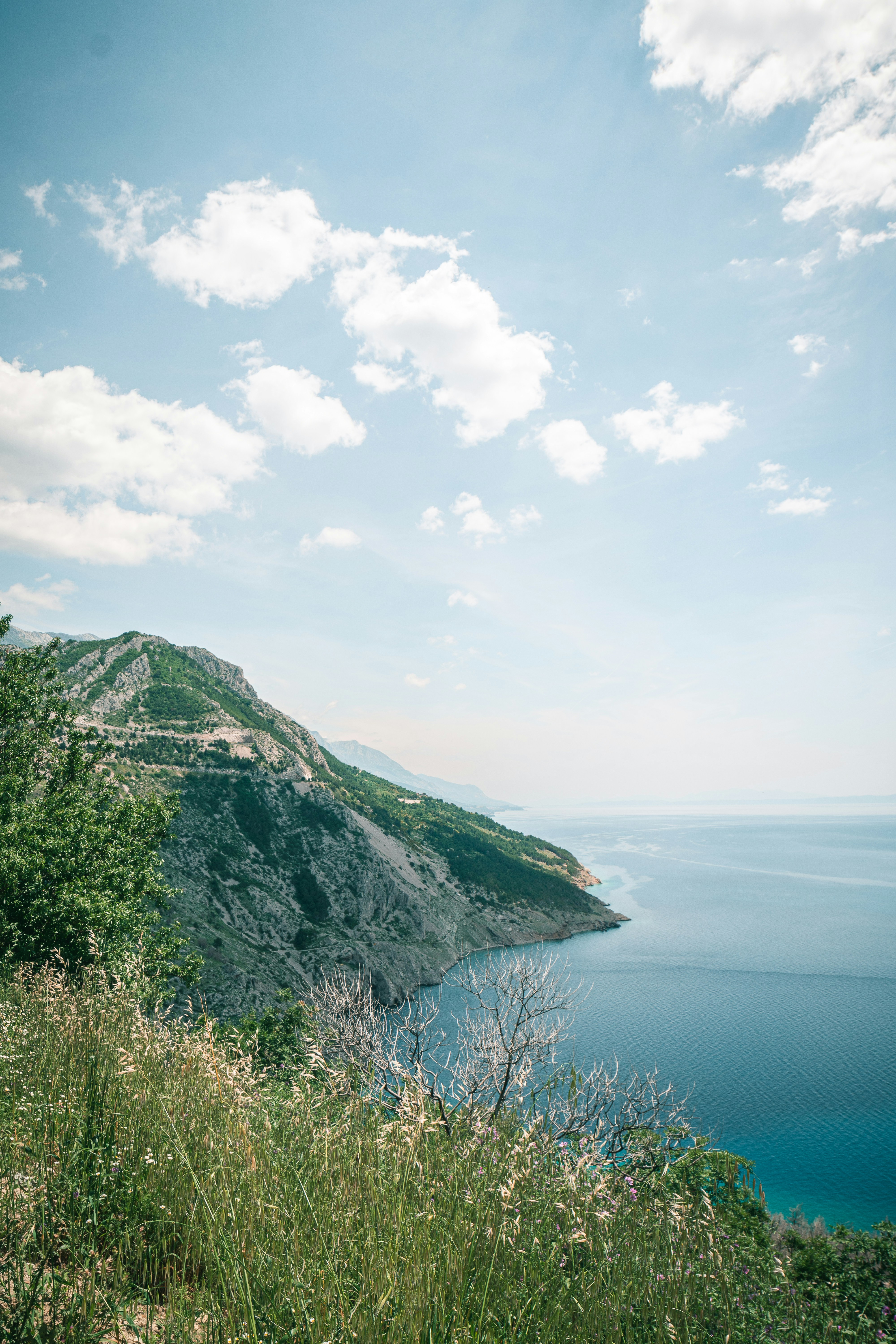 green mountain beside body of water under white clouds during daytime