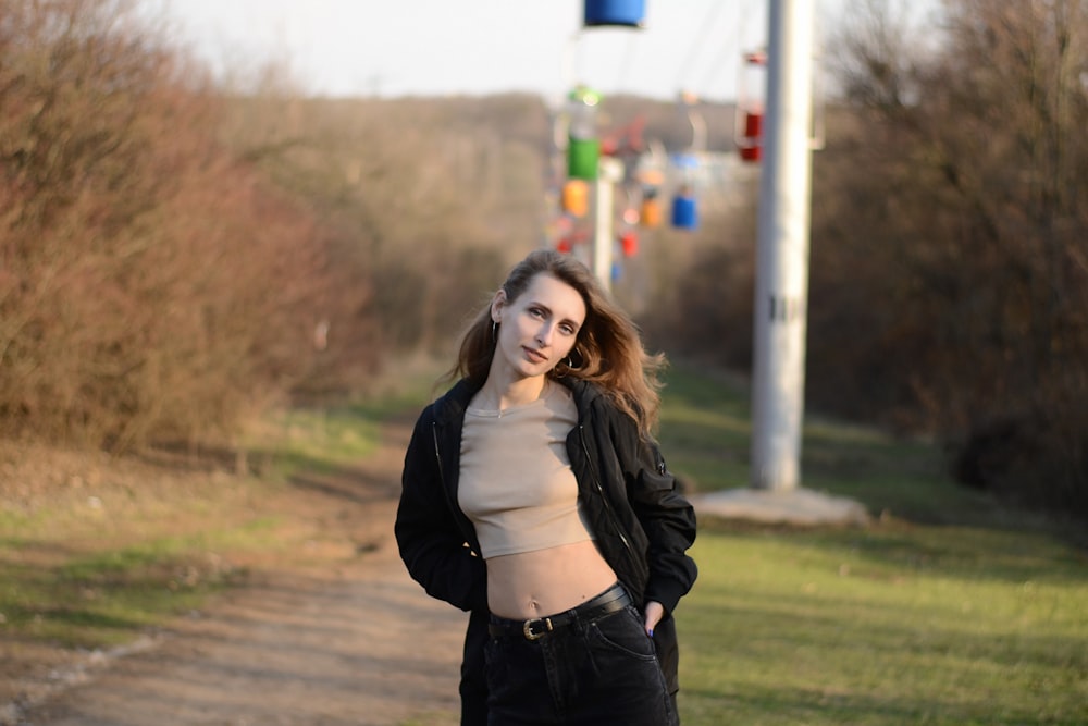 woman in black leather jacket standing on road during daytime