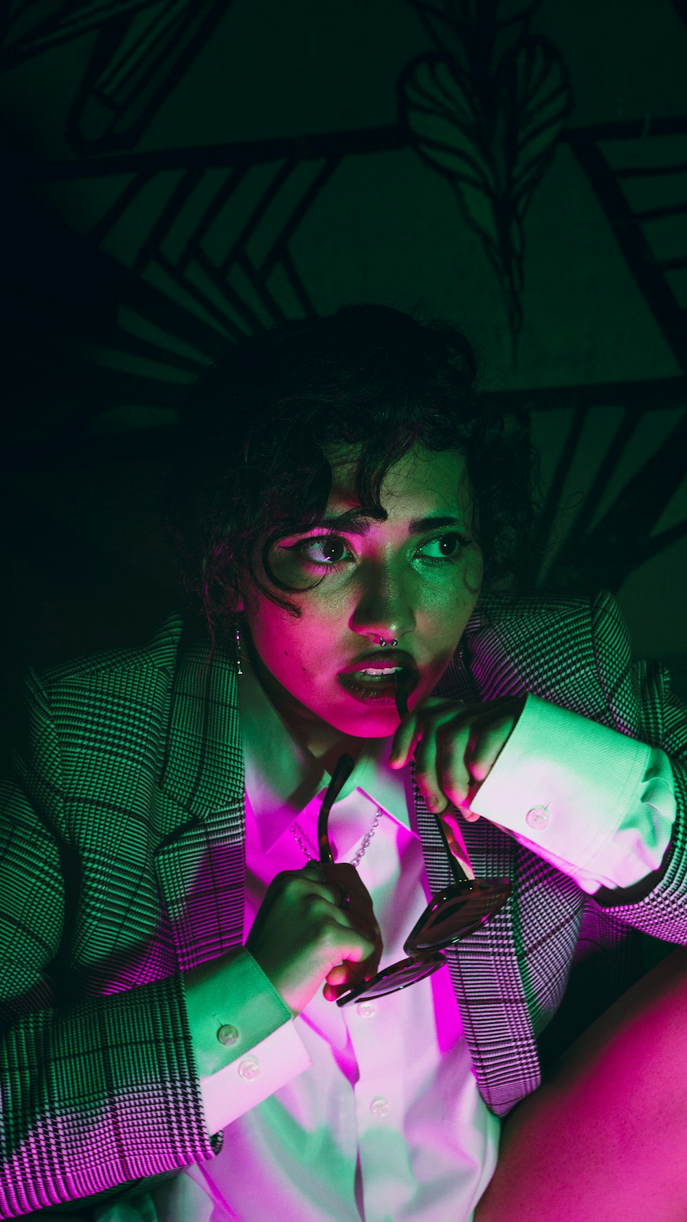 woman in gray and white pinstripe blazer holding green smartphone