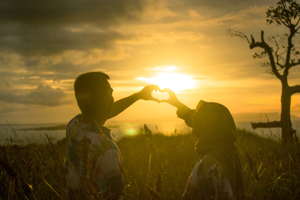 man in green and white floral button up shirt standing on green grass field during sunset