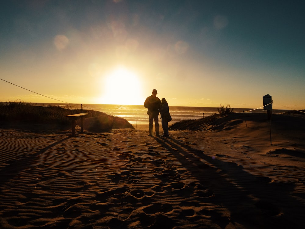 silhouette of 2 person walking on beach during sunset