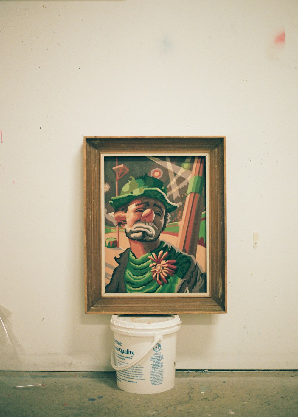 brown wooden framed painting of man in green and white hat