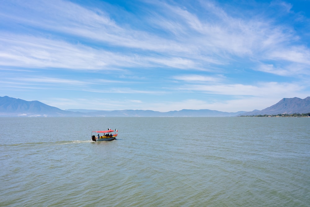 red boat on sea under blue sky during daytime