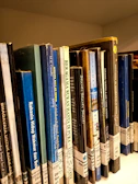 A shelf displaying books in Yiddish and Hebrew with colorful spines.