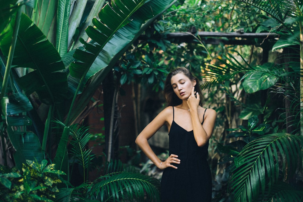 woman in black spaghetti strap dress standing beside green banana tree