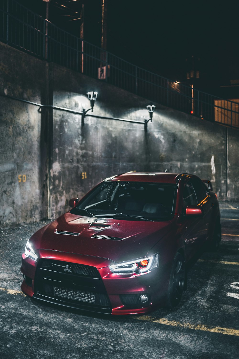 red honda car parked beside wall