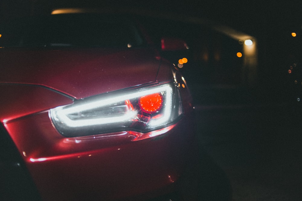 red car with white and yellow lights on during night time