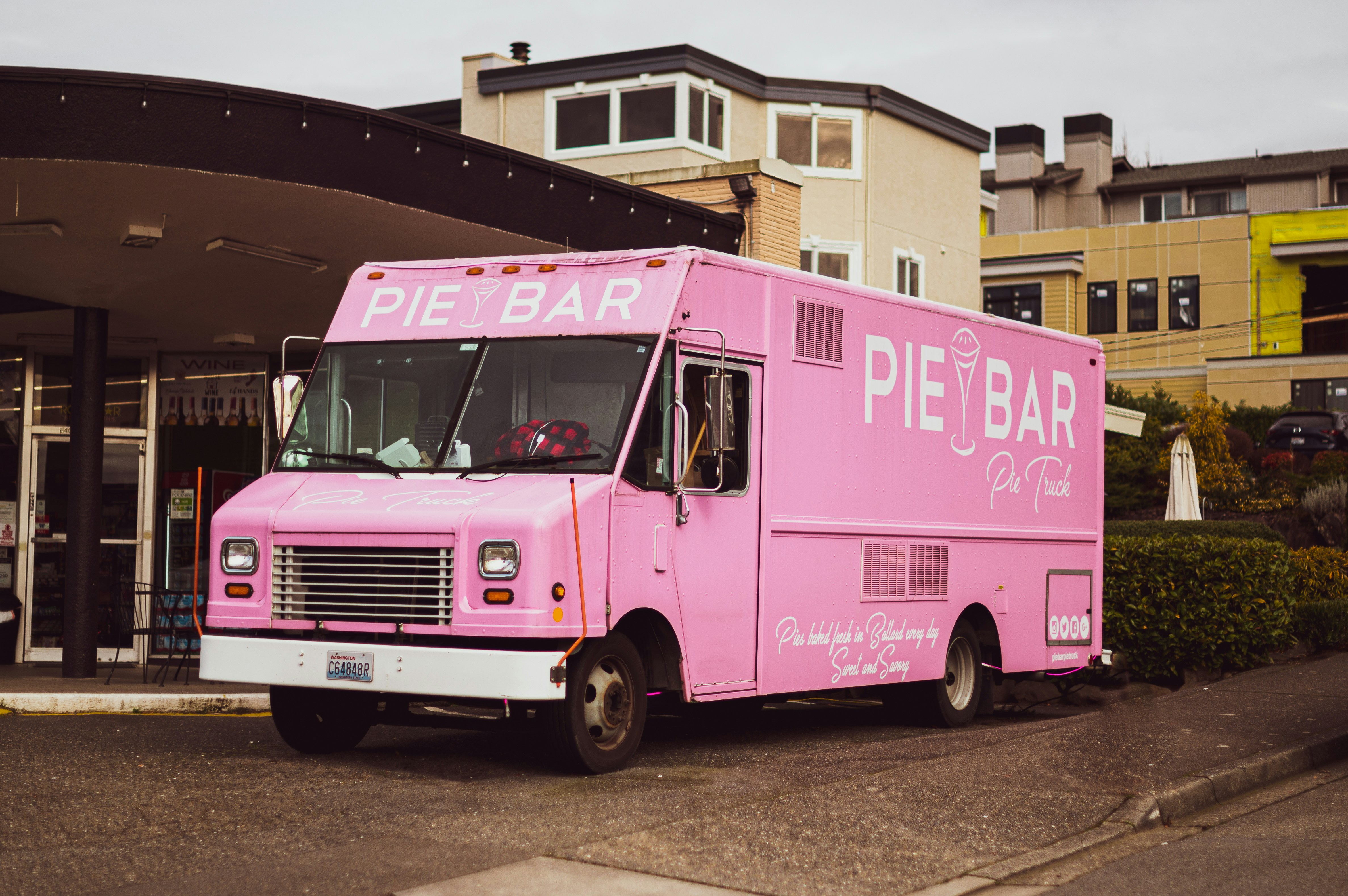 a pink food truck parked in front of a building