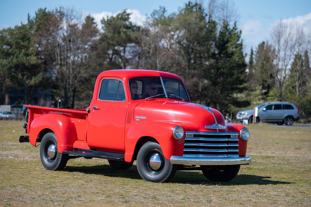 red vintage car on green grass field during daytime