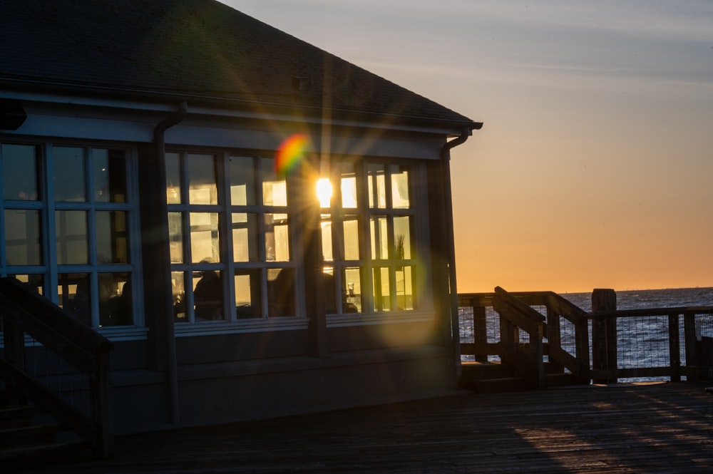 brown wooden house near body of water during sunset