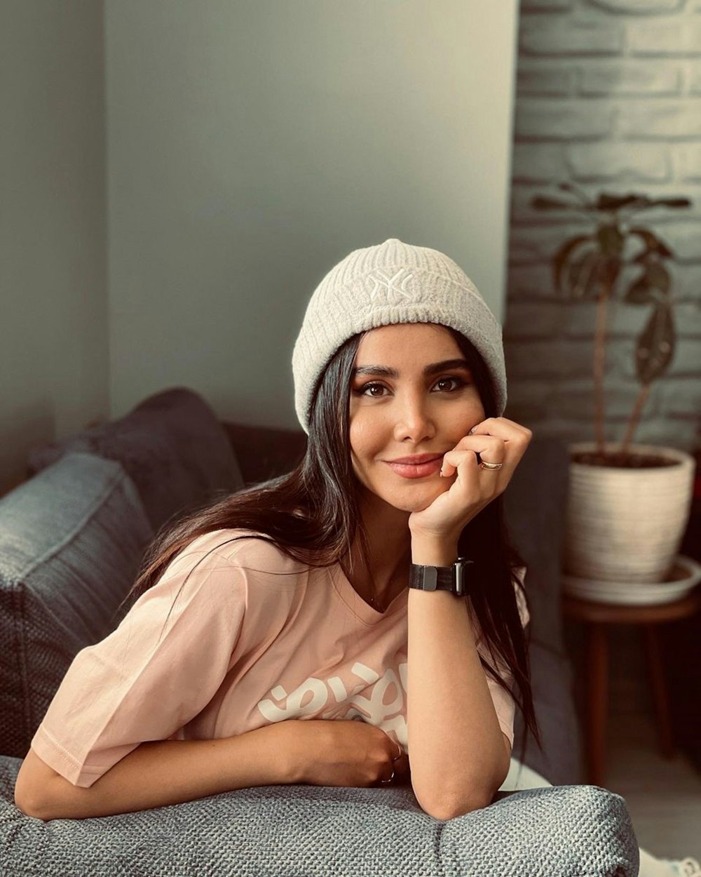 woman in pink shirt and white knit cap sitting on couch