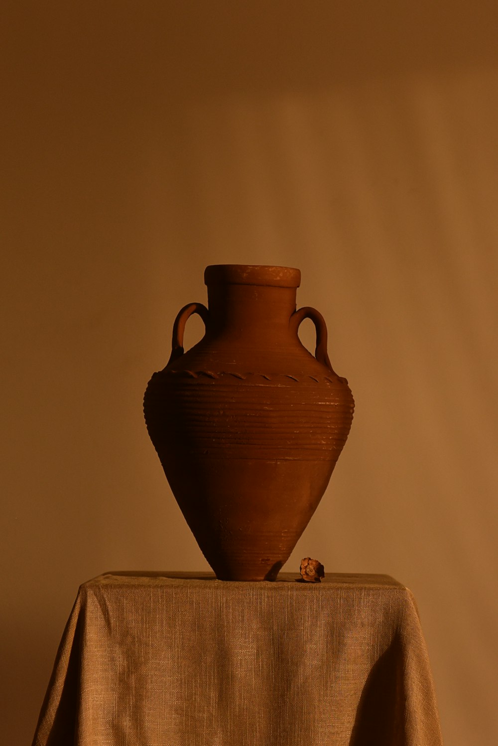 Jarrón de cerámica marrón sobre mantel blanco
