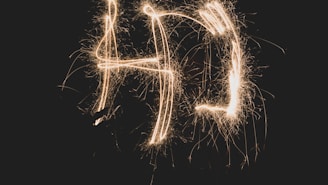 Light trails form the letters 'AD' against a dark background, creating an effect similar to sparklers.