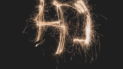 Light trails form the letters 'AD' against a dark background, creating an effect similar to sparklers.