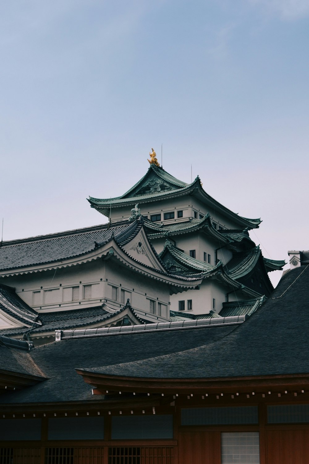 昼間の白い空の下に白と緑の寺院