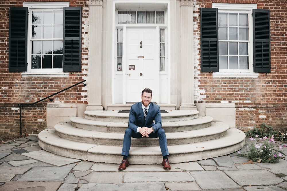 man in blue suit sitting on brown concrete stairs