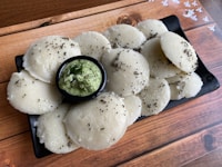 Close-up of golden ghee paddu balls arranged neatly on a rustic wooden platter.