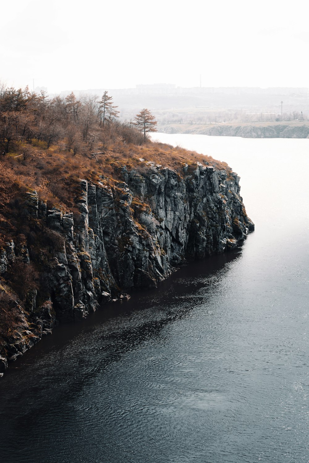 brown and green cliff beside body of water during daytime