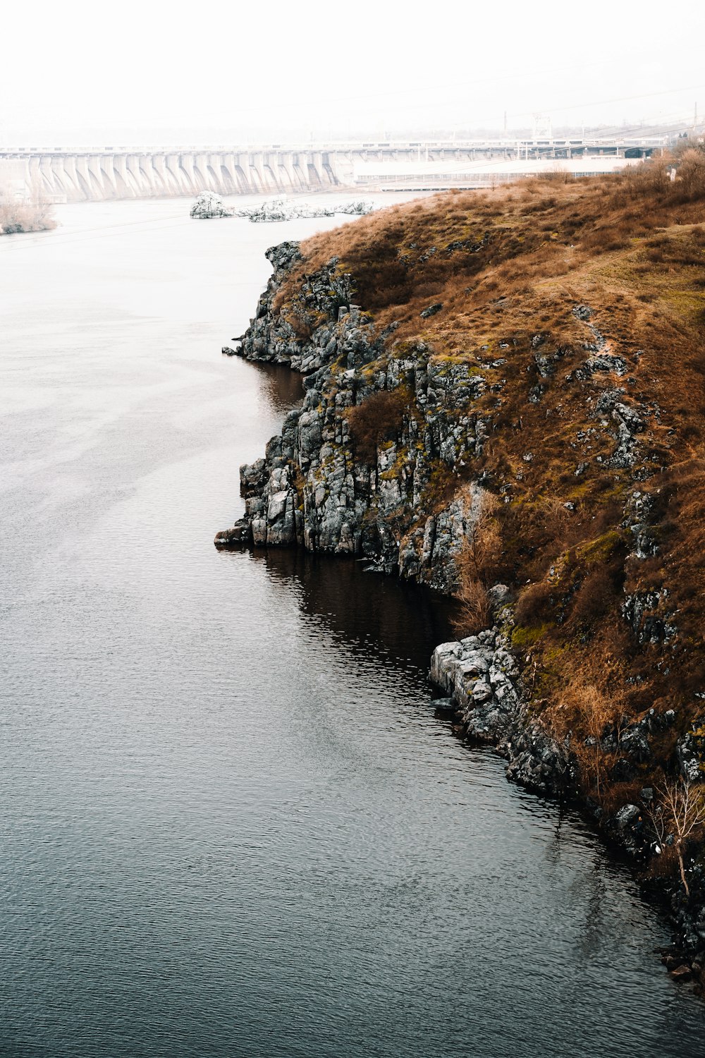 brown and green rock formation beside body of water during daytime