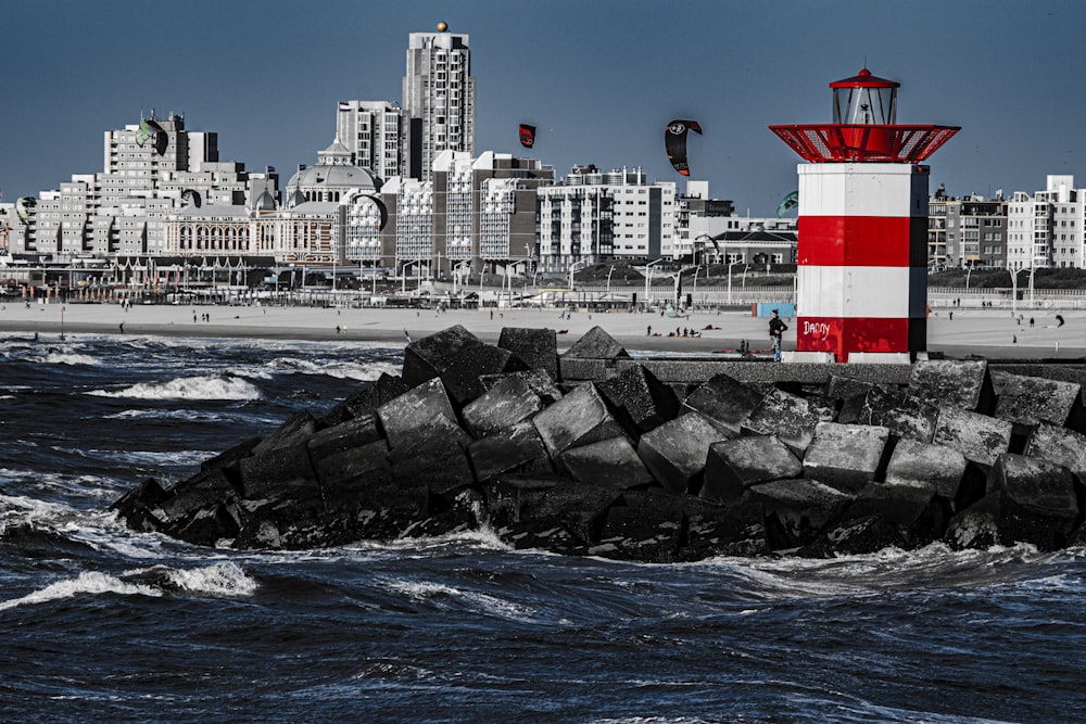 red and white lighthouse on rock formation near body of water during daytime