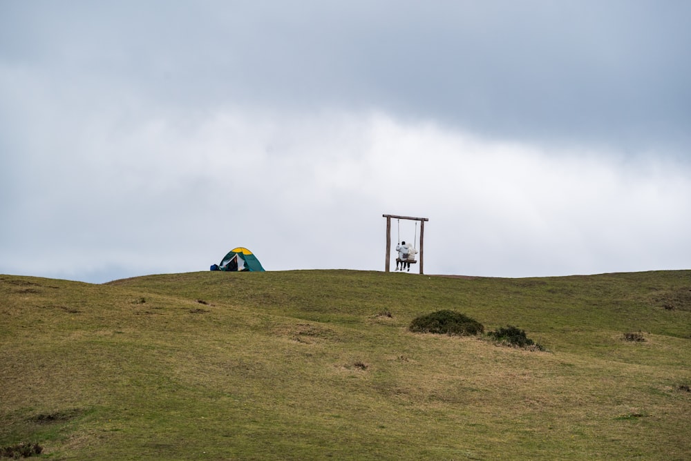 tente verte et jaune sur le champ d’herbe verte sous le ciel blanc pendant la journée