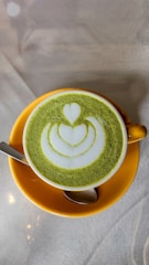 A delicate cup of frothy matcha latte with a soft pastel pink background, embodying youthful charm.