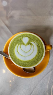 A delicate cup of frothy matcha latte with a soft pastel pink background, embodying youthful charm.