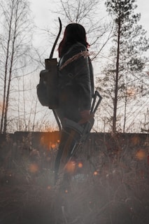 Leather quiver hanging from a tree branch in a sunlit forest setting.