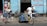 A scene in front of a bicycle repair shop with three men and several bicycles. One man is working on a bike while another leans against the wall, engaging in conversation. A tricycle with blue water containers also occupies the foreground. The building is painted light blue with signage in red lettering.