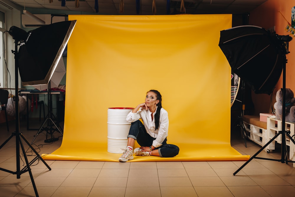 Femme en chemise blanche à manches longues assise sur des carreaux de sol jaunes