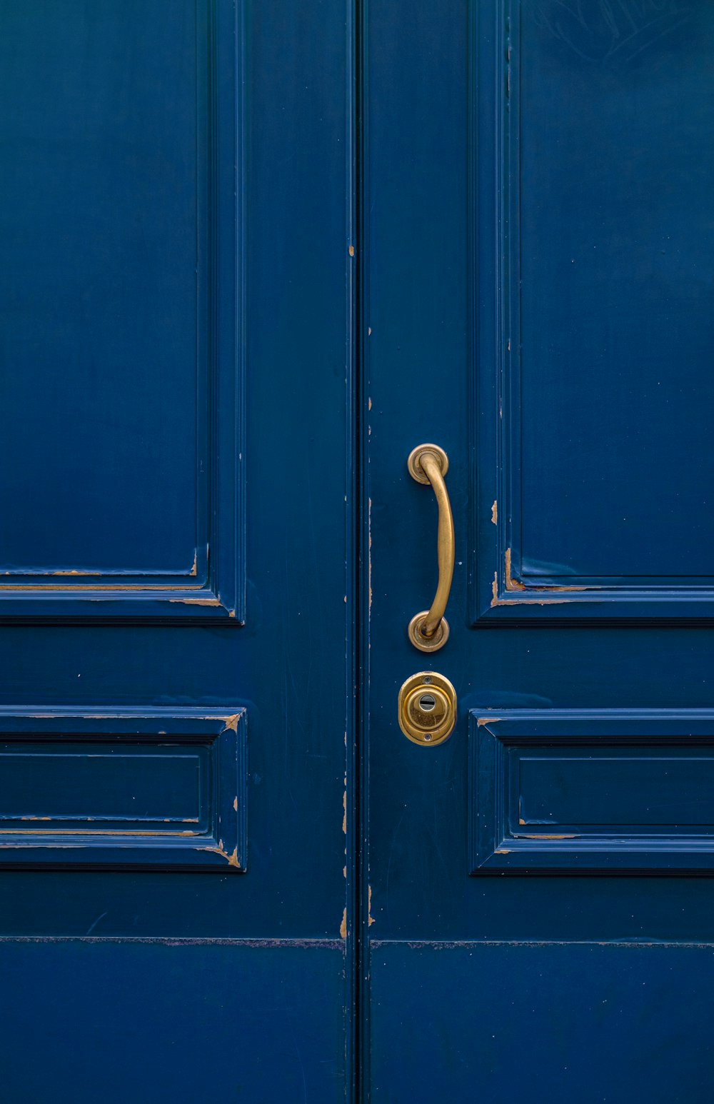 blaue Holztür mit goldenem Türhebel