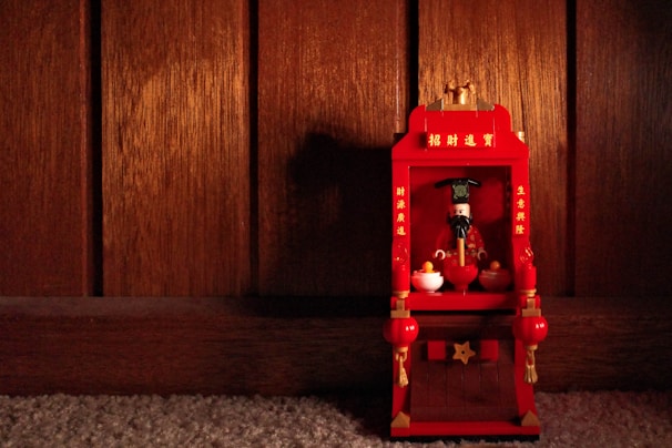 A softly glowing LDS temple replica displayed on a wooden shelf with family photos nearby.