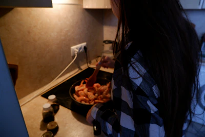 Bright urban kitchen scene with a young person preparing shrimp and vegetable instant soup.