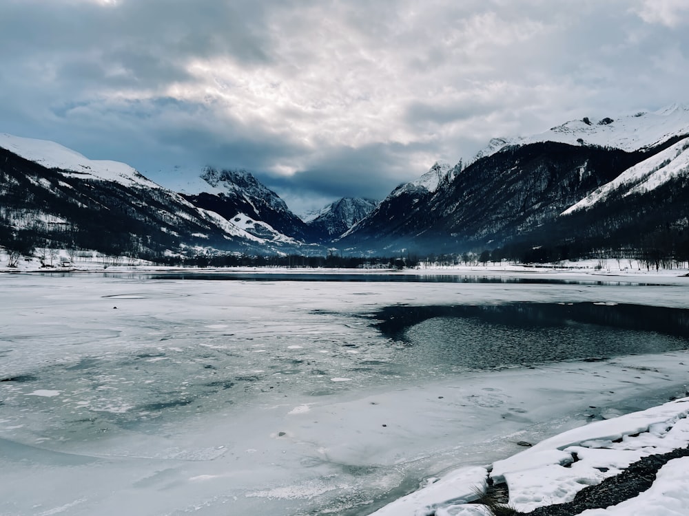 snow covered mountain near body of water during daytime