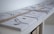 Stacks of neatly bound papers or envelopes are arranged on a white shelf. Each stack is secured with a brown band, and the items appear to have minimalistic black and white designs on their surfaces.