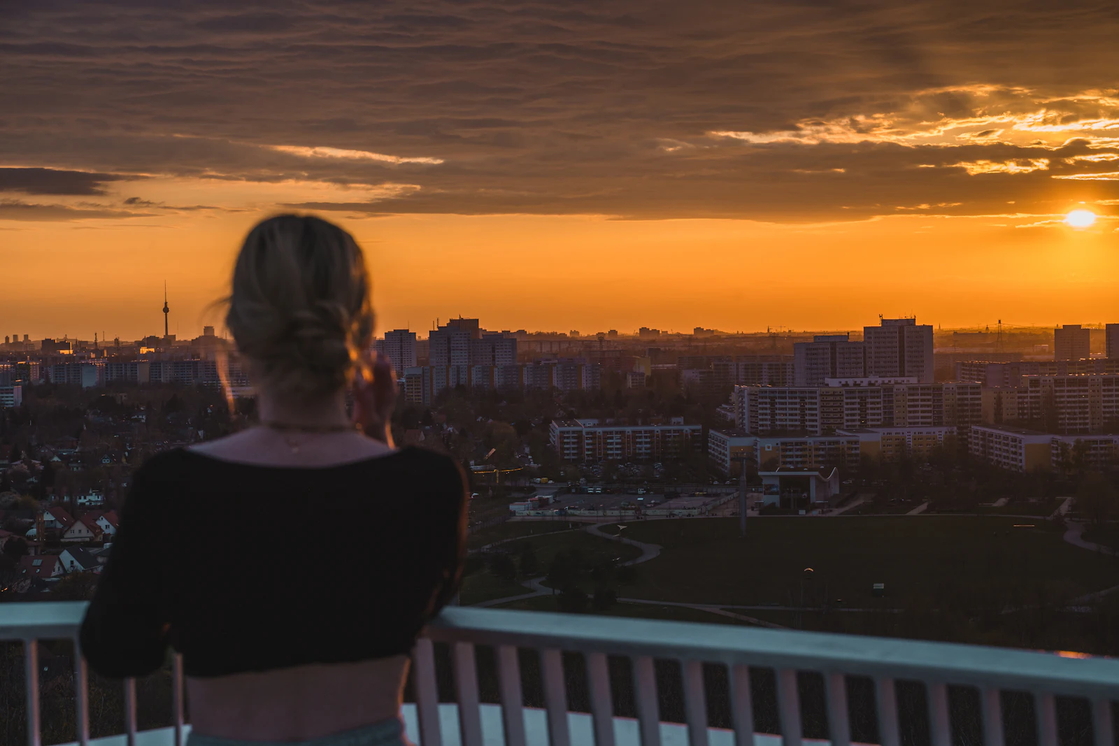A woman looking out over a city at sunset