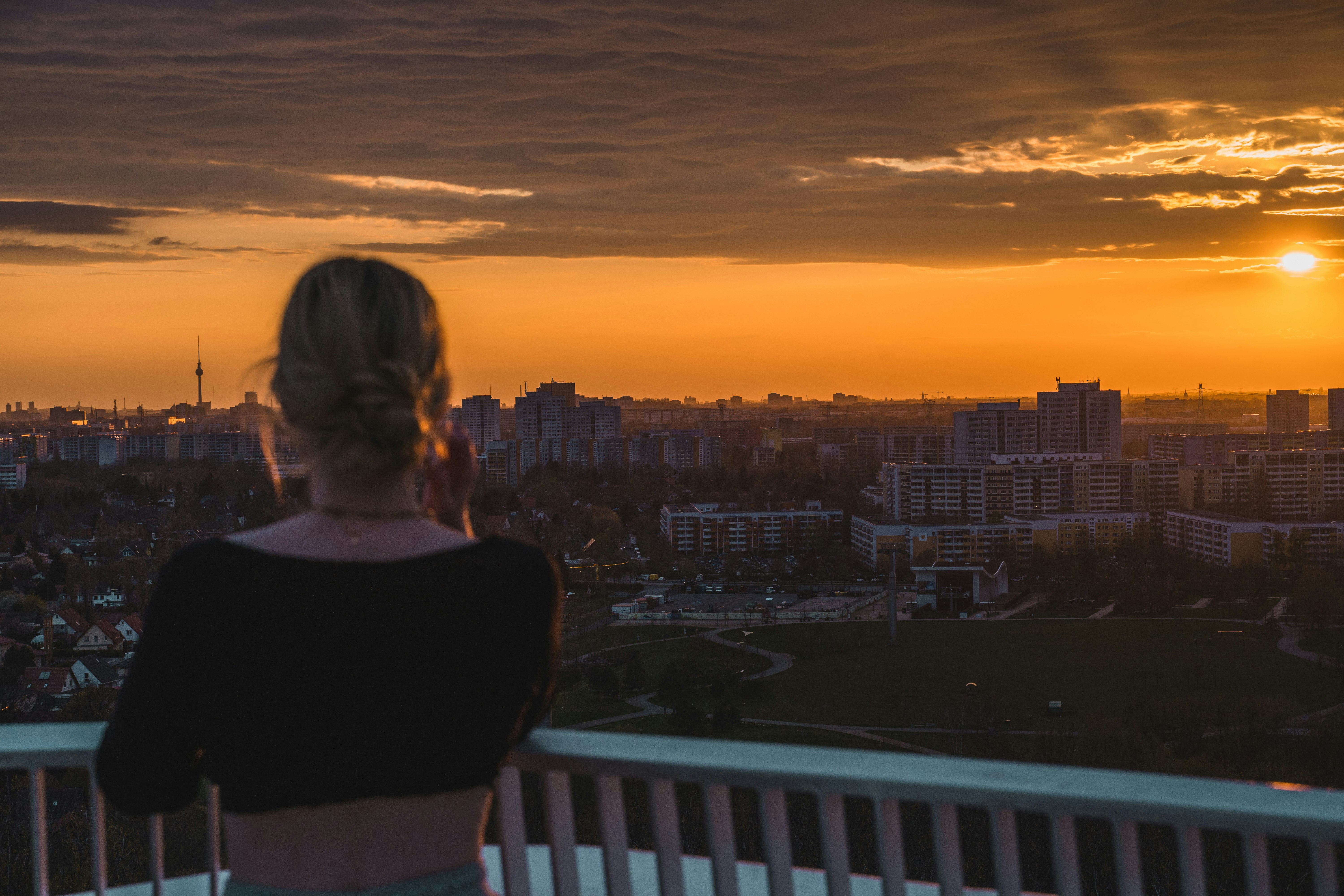 woman in black shirt standing on balcony during sunset