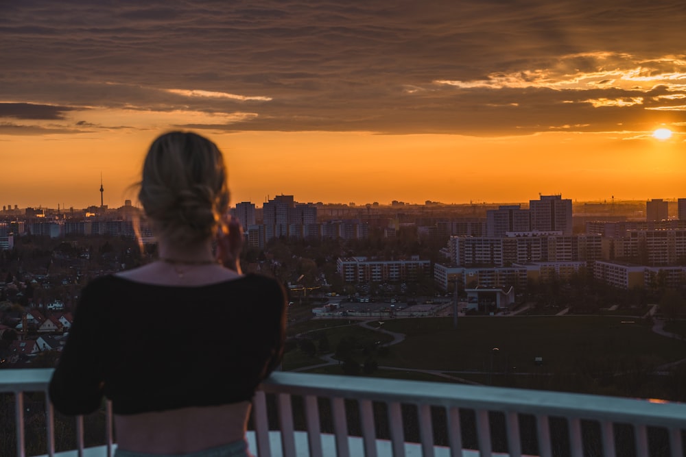 woman in black shirt standing on balcony during sunset