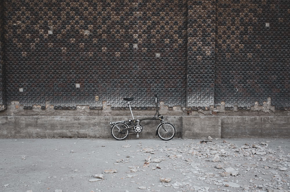 bicicletta nera su muro di mattoni marroni