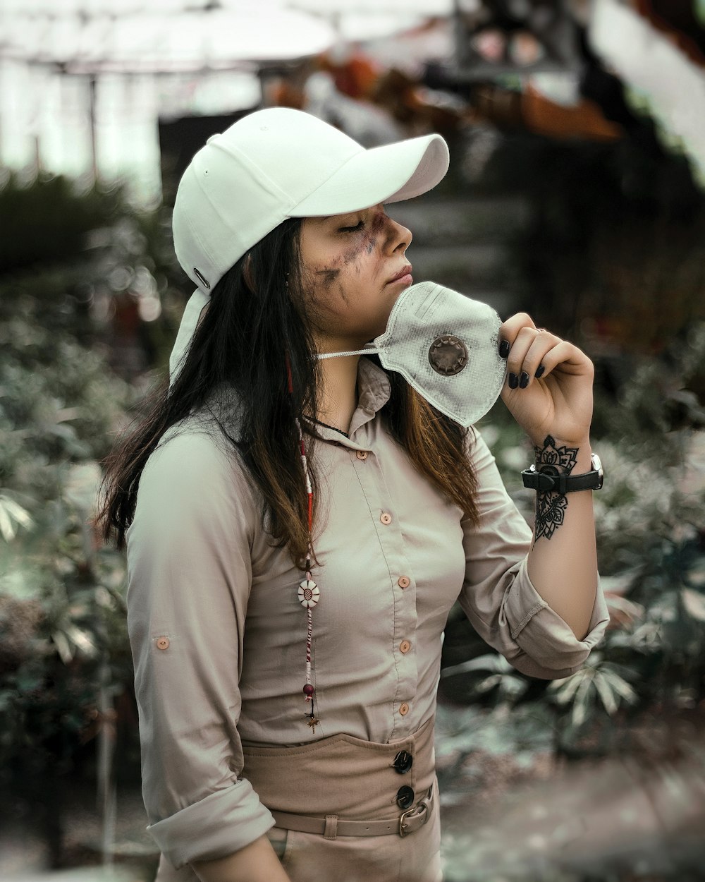 Femme en chapeau blanc et chemise blanche à manches longues tenant un appareil photo noir et blanc